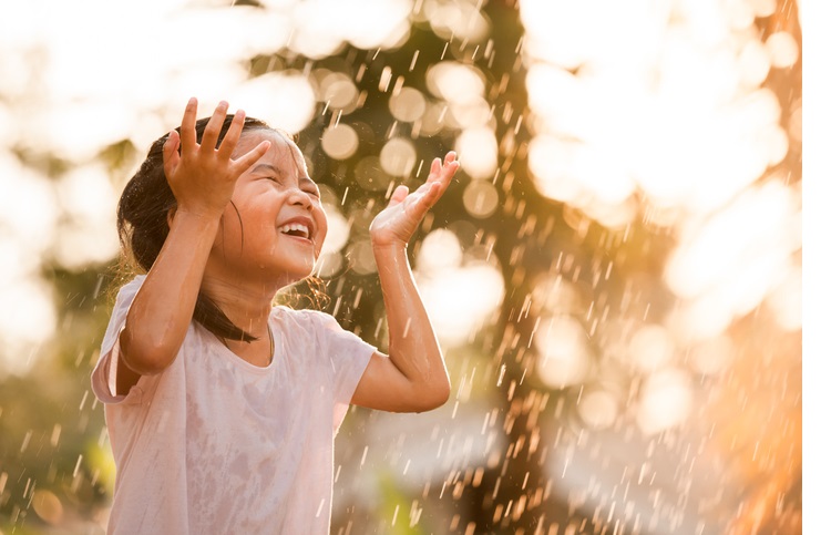 Happy asian little girl having fun to play with the rain in vintage color tone